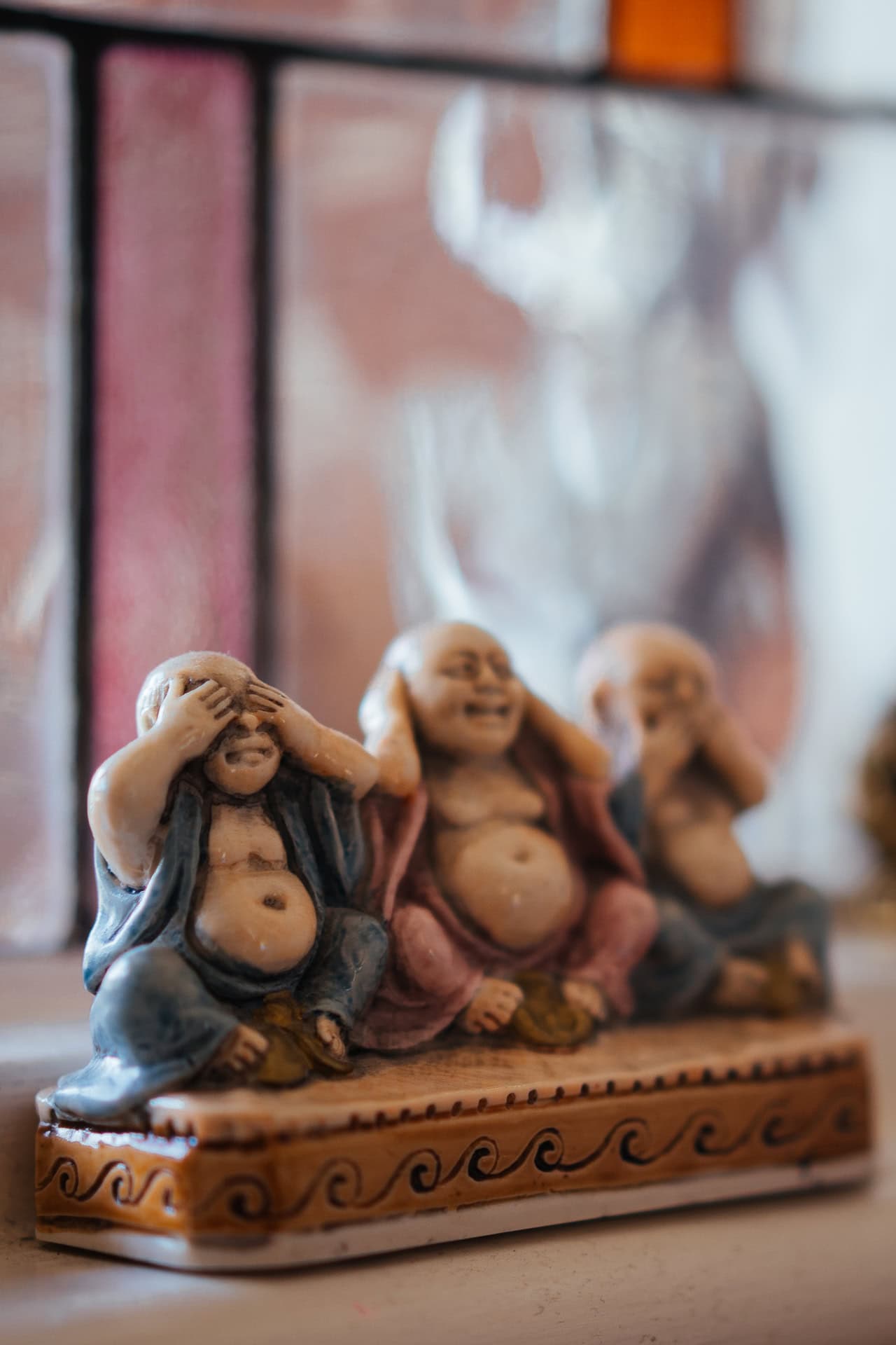 Three Wise Monkeys figurines representing see no evil, hear no evil, speak no evil, in a soft focus setting.