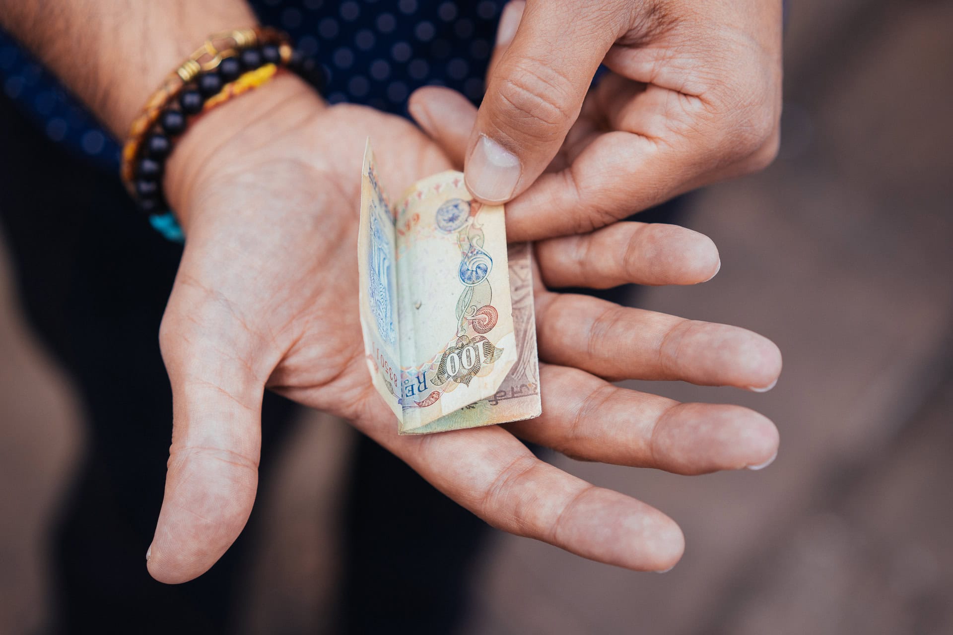 Dipak Dave holds a 100 Rupee note, showcasing a detail of his personal brand photography.