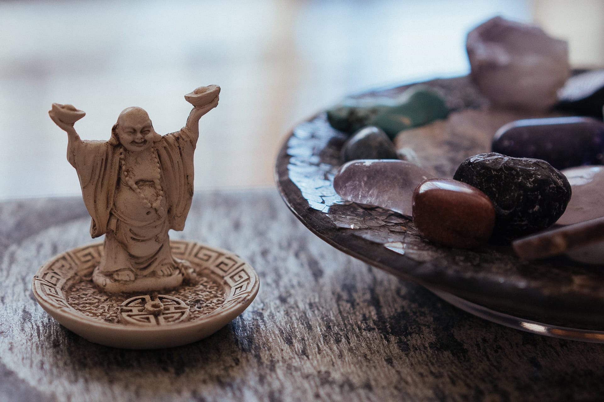 A serene Buddha figurine and a collection of polished crystals on a rustic wooden surface.