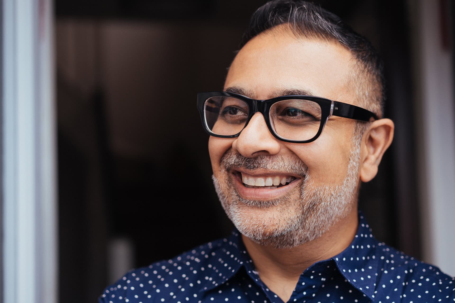 Dipak Dave, a confident man with a warm smile, captured in soft, natural light by a London brand photographer.