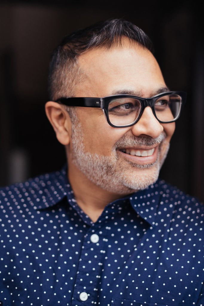 Dipak Dave, a London brand photographer's client, smiles warmly in a natural light portrait.