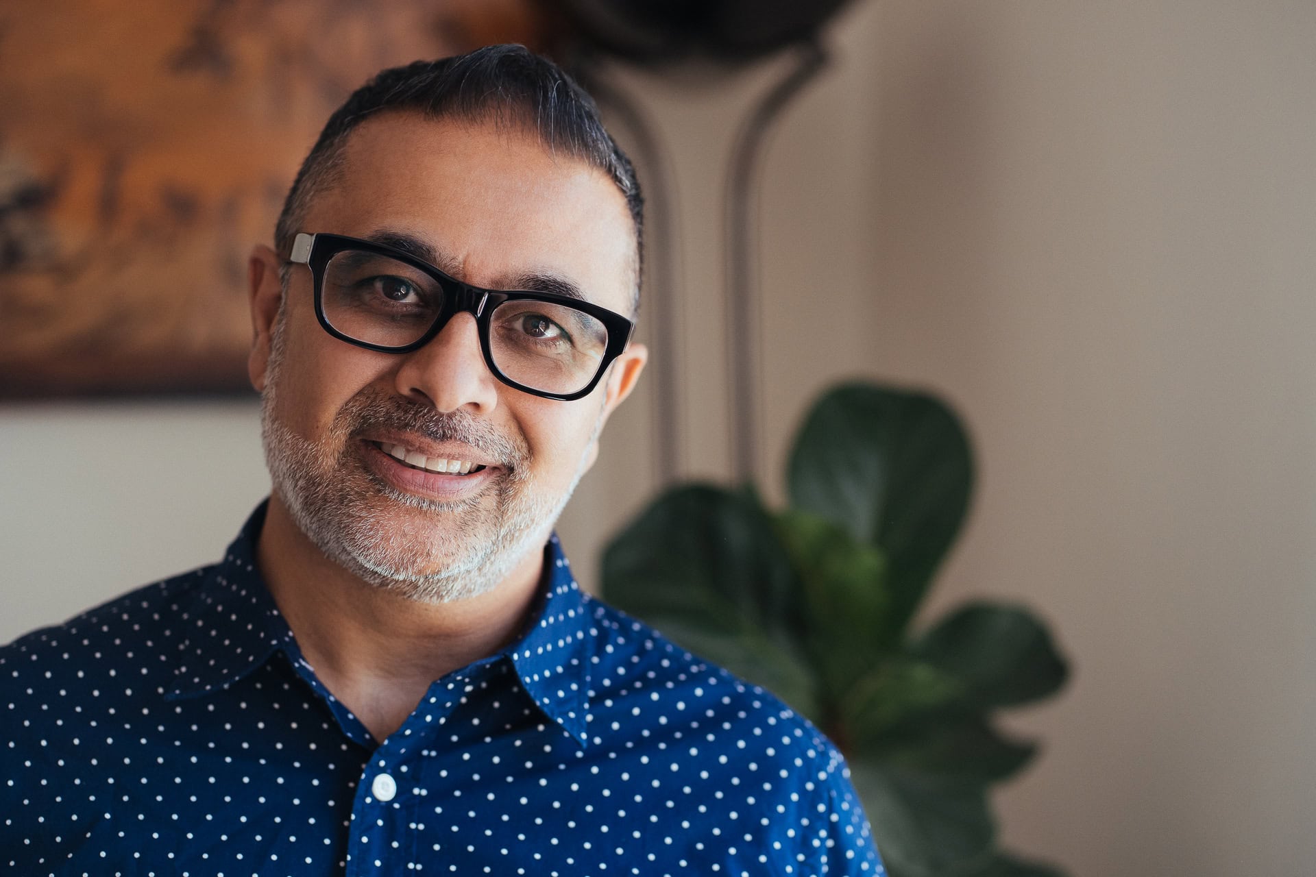 Dipak Dave, a coach, smiles confidently in natural light, captured by a London brand photographer.
