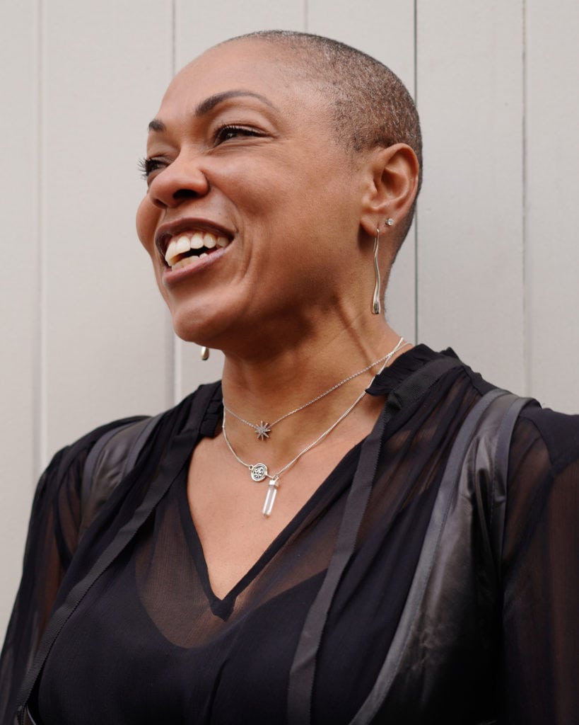 Sharlene Jones, a woman with a radiant smile and stylish jewellery, photographed by a London brand photographer.