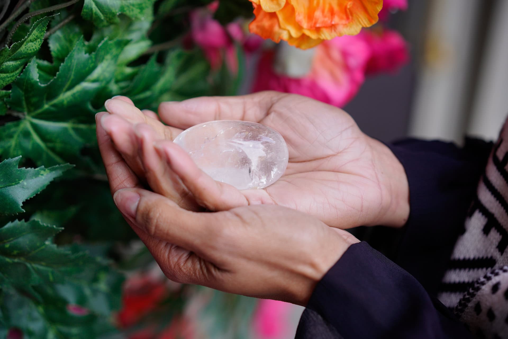 Sharlene Jones holds a clear crystal, with soft light illuminating her hands and a hint of colourful flowers.