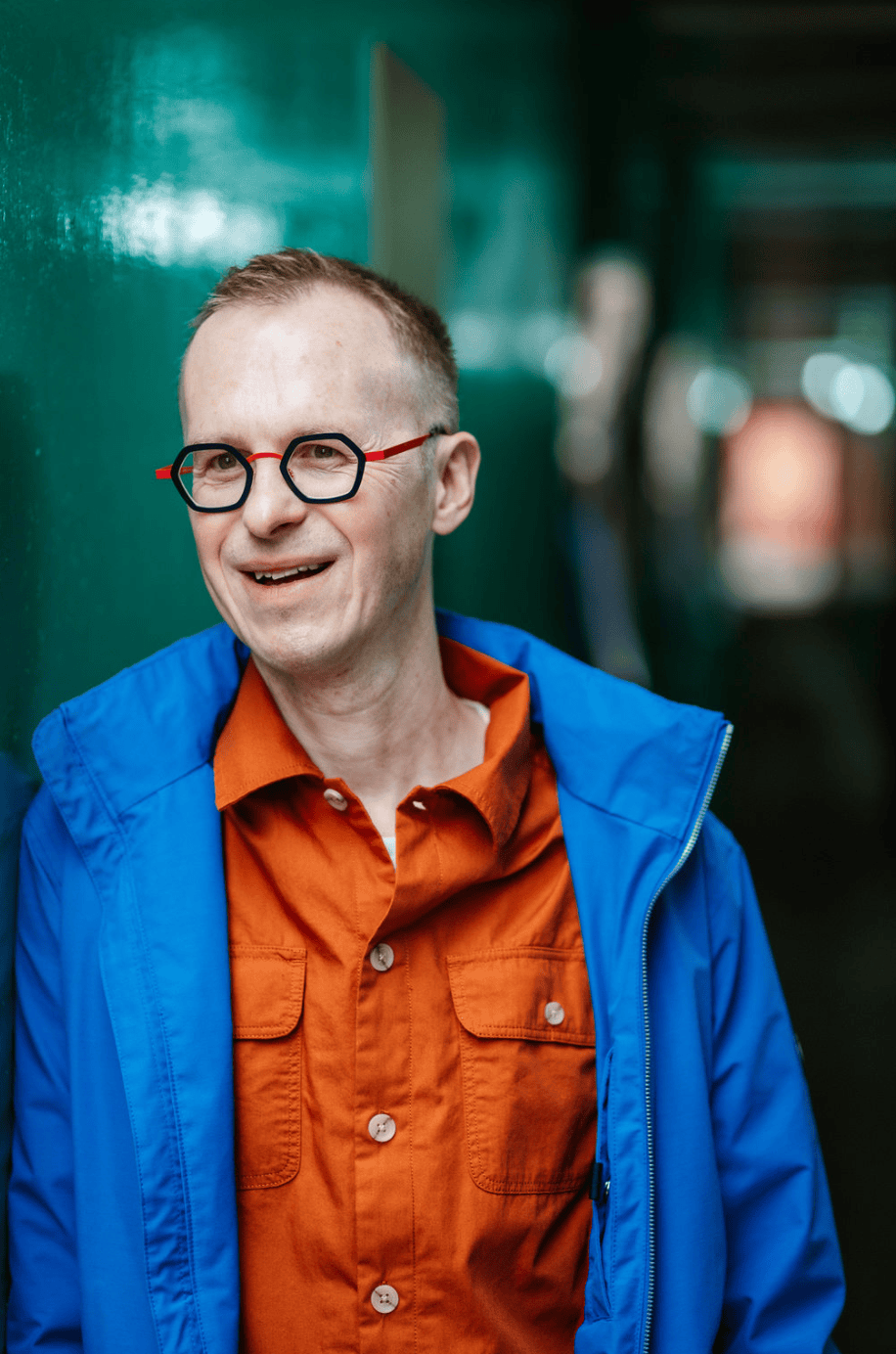 Richard Jones, a confident coach, smiles warmly in a London setting, captured by a brand photographer.