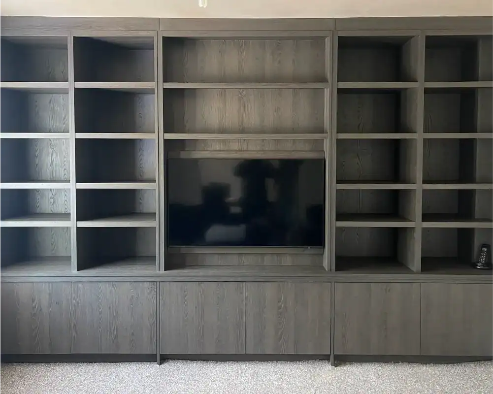 Custom-made wooden media wall with integrated shelving and storage solutions.