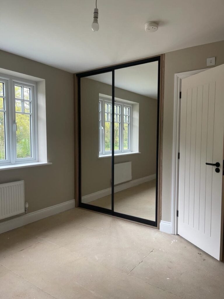 Built-in wardrobe with mirrored sliding doors in a modern bedroom.