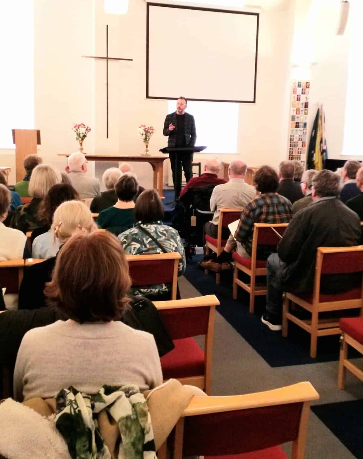 A man speaking at a church event in front of an audience during a community gathering.