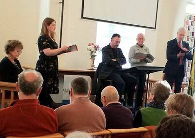 Female speaker reading at Oriana Choir Macclesfield event.