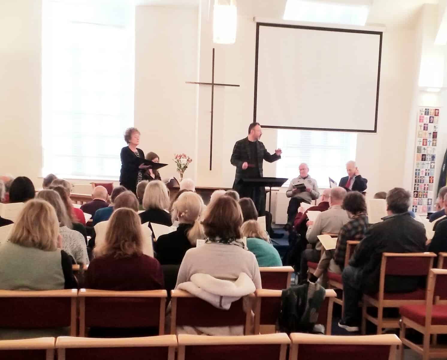 Aural performance by Macclesfield Oriana Choir at a church, showcasing choir singers and director.