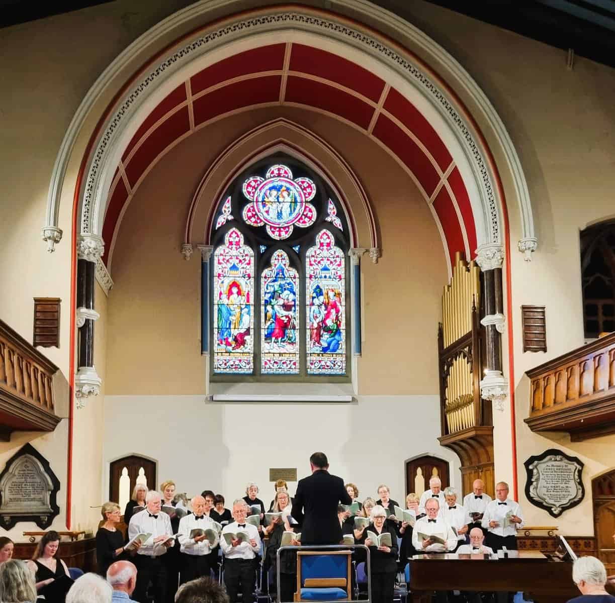 Oriana Choir Macclesfield performing inside a historic church with stained glass windows.