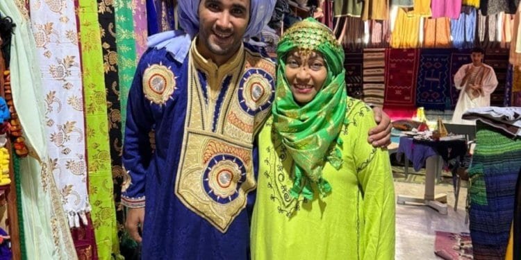 Pareja con ropa tradicional marroquí en mercado colorido.