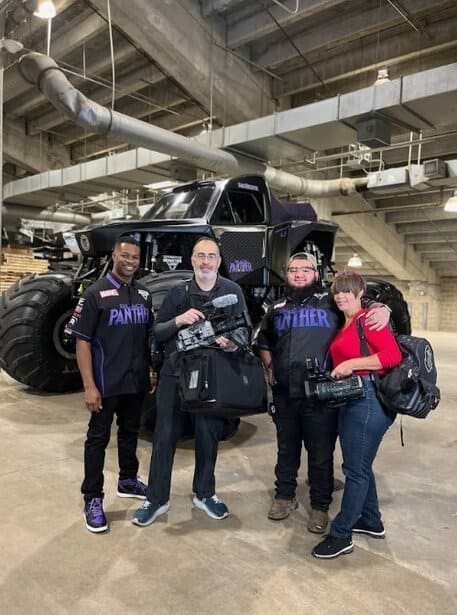 Large futuristic vehicle with four people posing in an industrial setting.