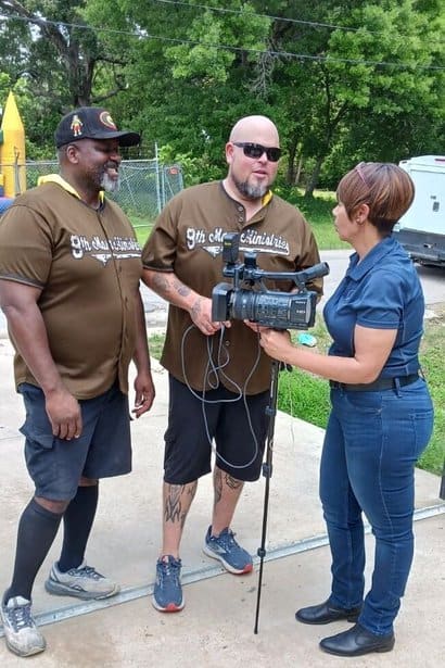 Footage of two men and a woman recording an interview outdoors in a park setting.