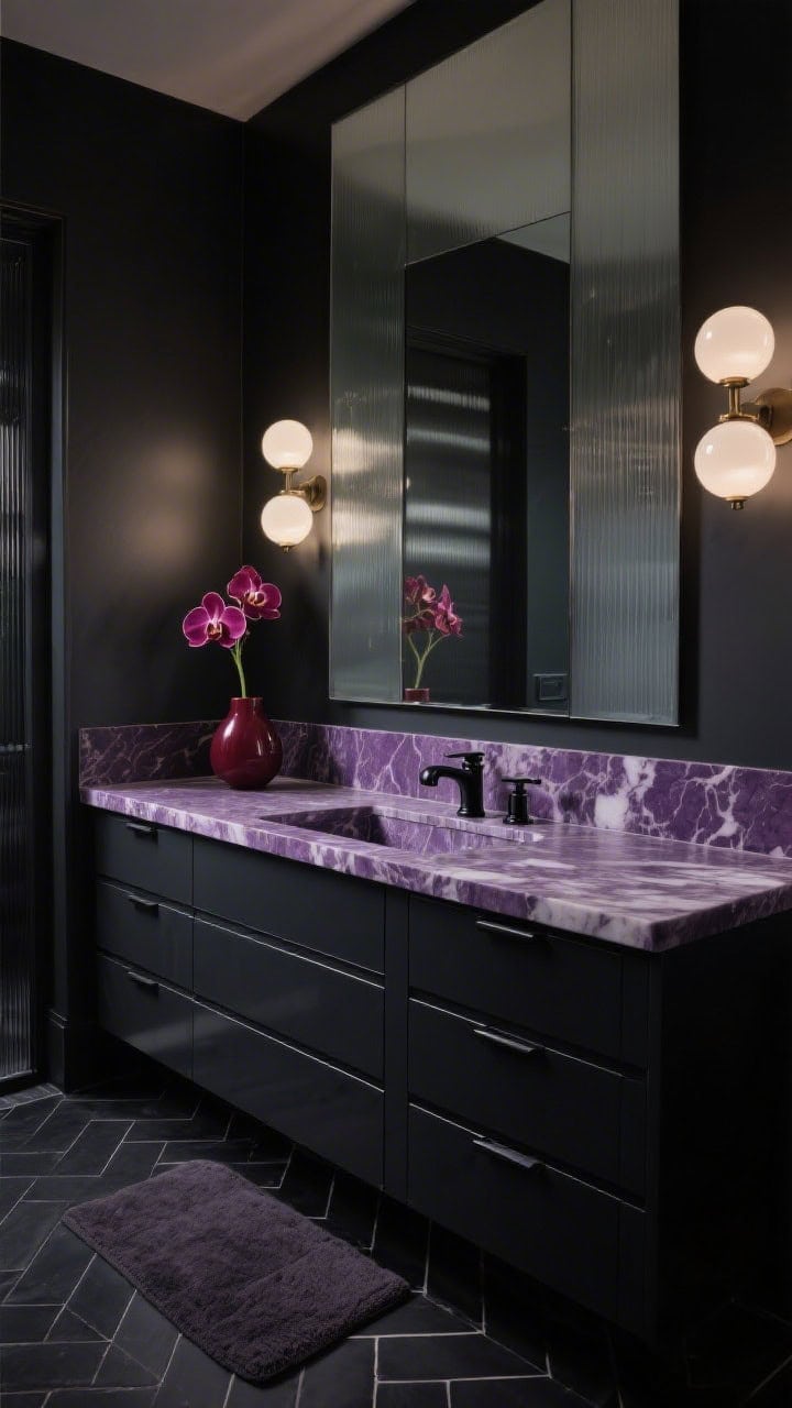 Photorealistic straight-on medium shot of a moody luxe vanity: deep charcoal lacquer cabinet with flat-front drawers, bold thick Calacatta viola countertop with dramatic violet veining; brushed black nickel faucet and hardware; oversized single mirror mounted on a smoked glass panel that spans the wall; domed opal glass sconces glowing softly; black herringbone tile floor and plush charcoal bath mat; a deep burgundy orchid in a minimal vase for a striking accent.