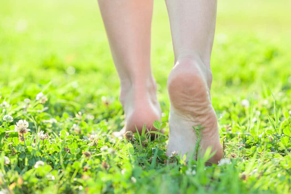 Bare feet walking on grass representing grounding and a natural healthy home journey