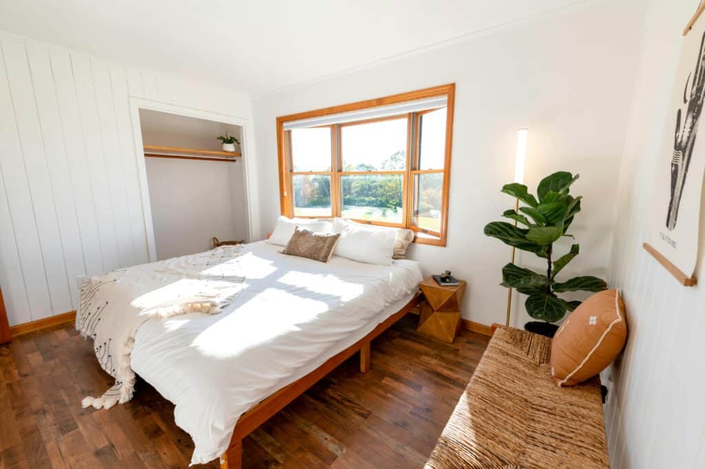Bright and airy bedroom with wooden floor and modern decor, perfect for relaxation.