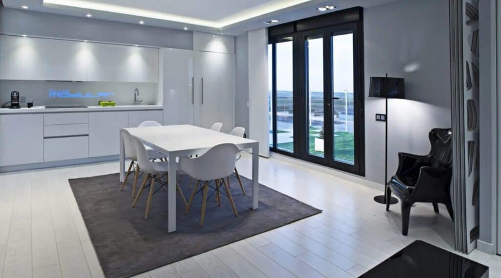 Cocina moderna blanca con mesa y sillas.