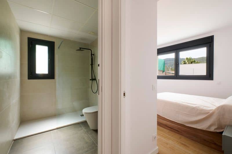 Baño y dormitorio minimalista con ventanas grandes.