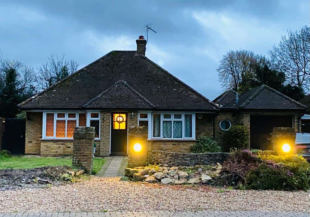 Modern house with loft conversion and outdoor lighting at dusk.