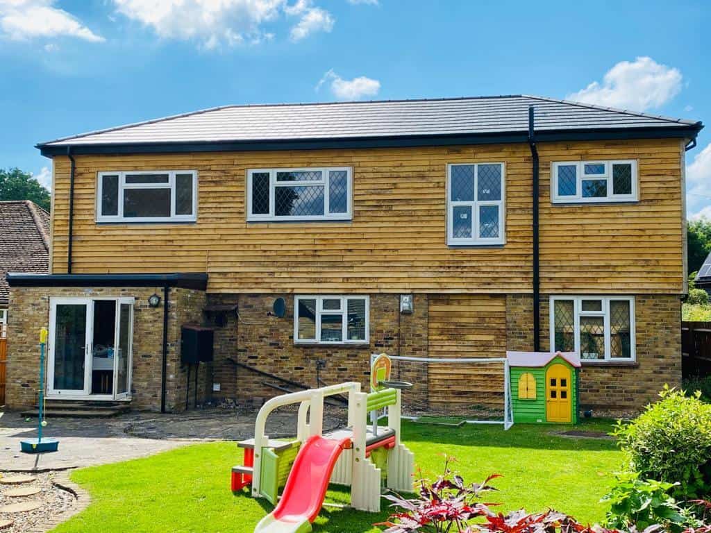 Contemporary two-storey wooden house with garden and children's play area.