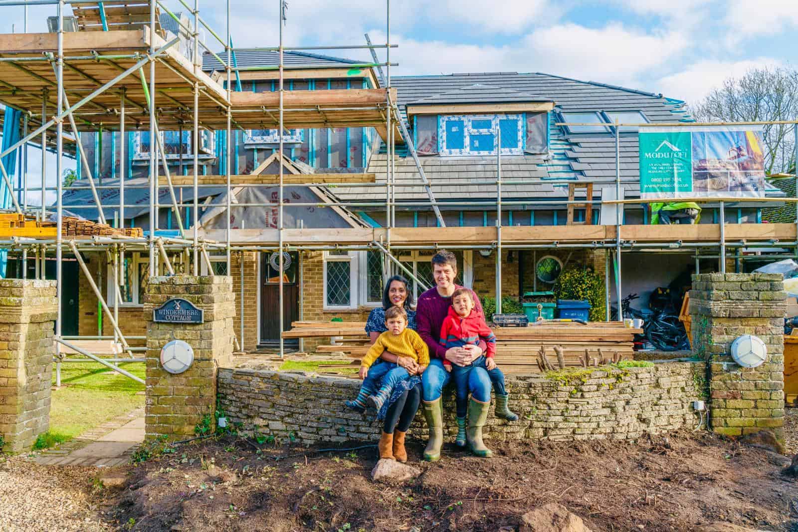 Family sitting outside a new Moduloft home under construction with scaffolding.