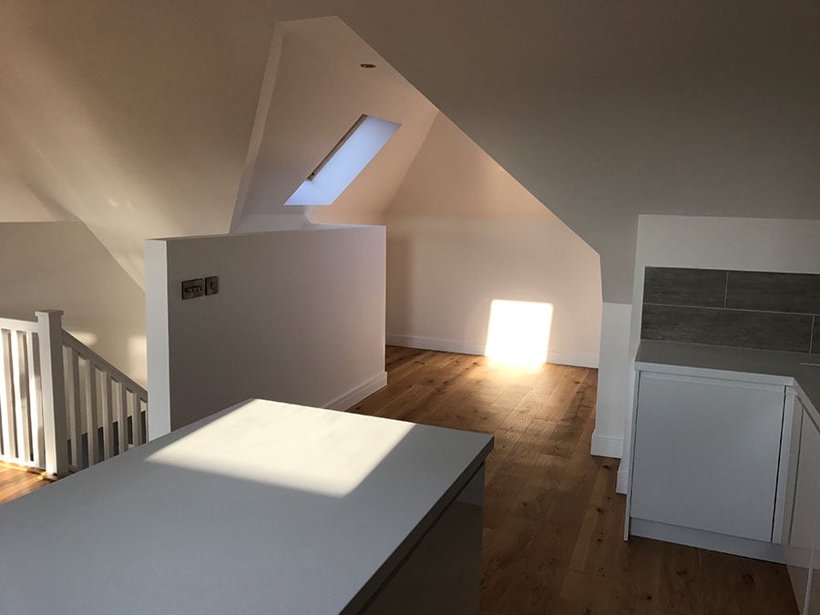 Modern loft space with skylights and wooden flooring.