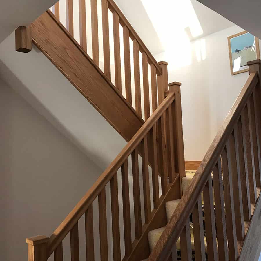 Elegant wooden staircase with beige carpet runner in modern home.