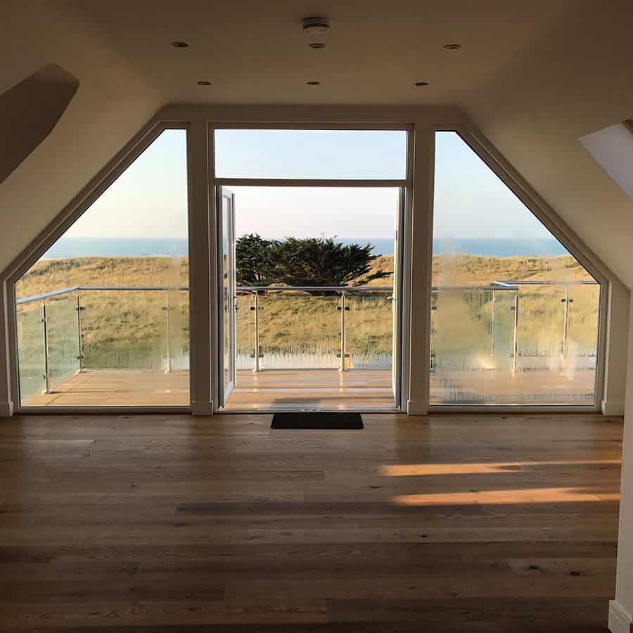 Loft balcony with glass railing overlooking beach and dunes.