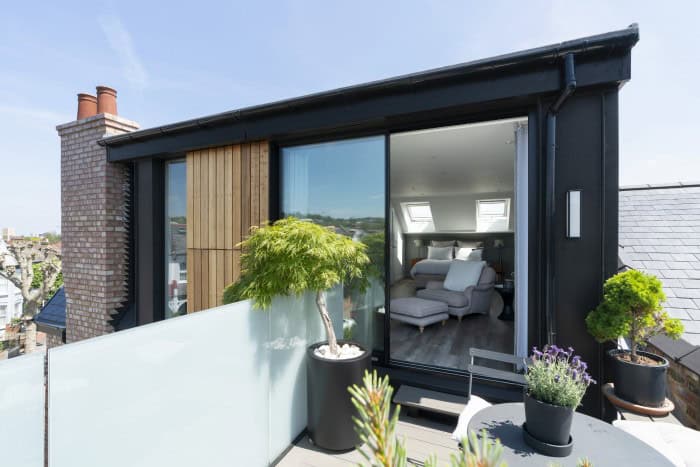 Contemporary loft with rooftop terrace, large glass doors, and outdoor plants.