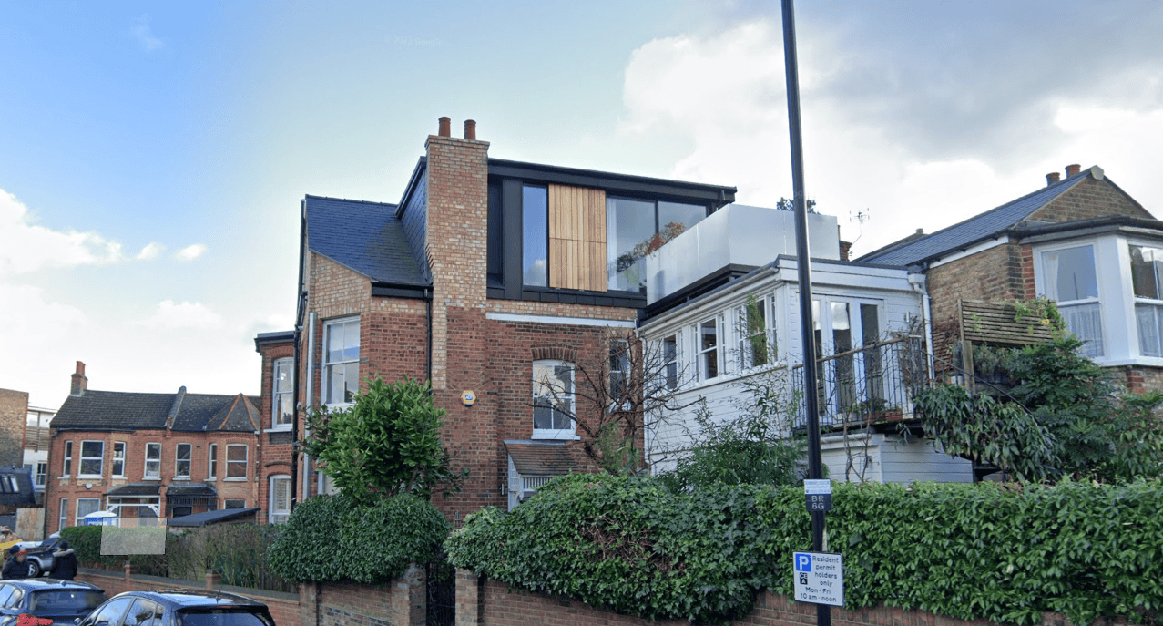 Modern rooftop extension on a traditional brick house in an urban setting.
