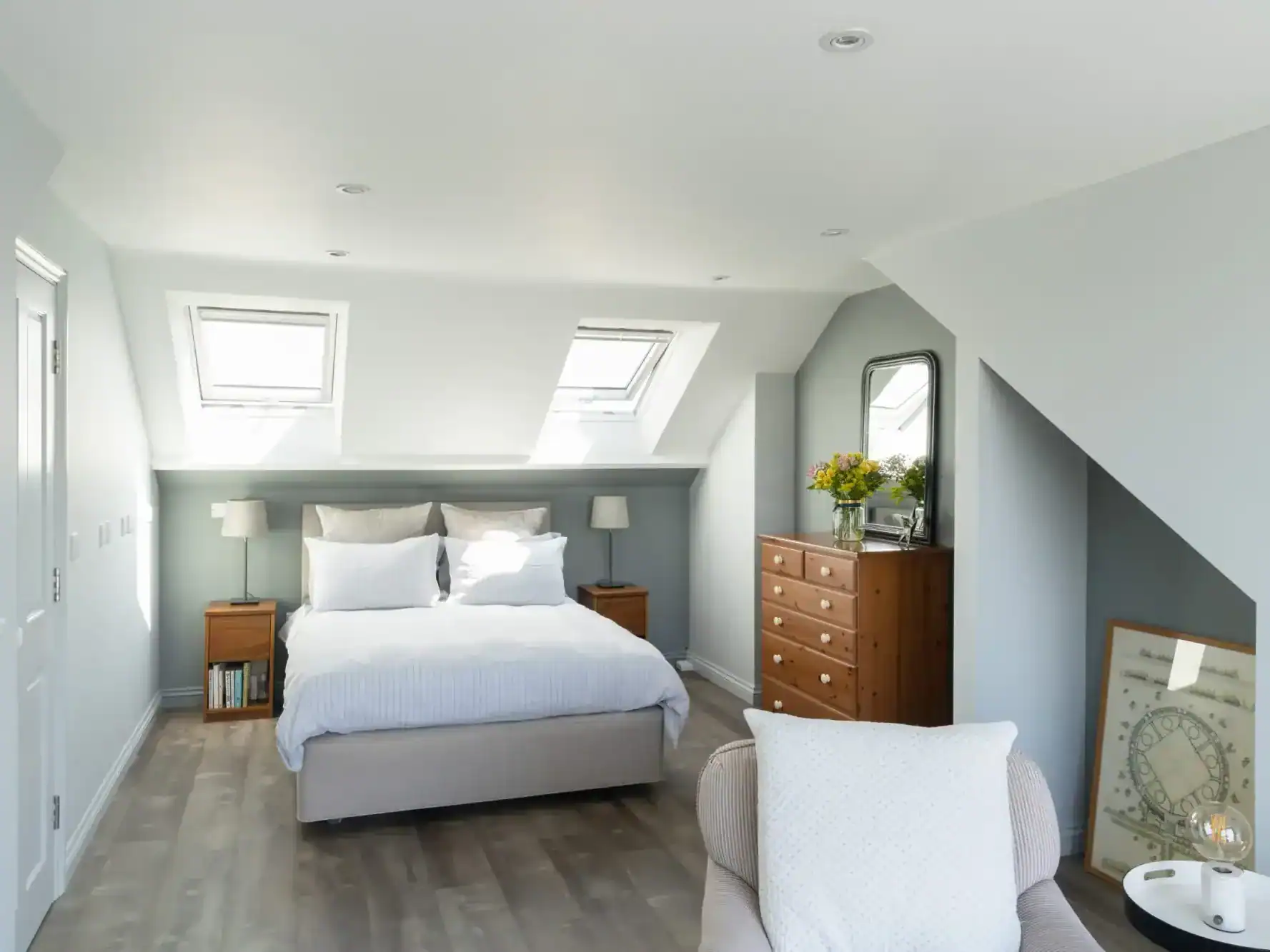 Bright attic bedroom with skylights and modern decor for loft conversion.