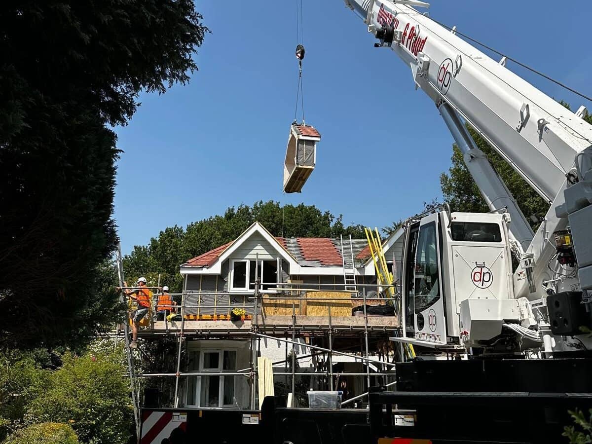 Crane lifting a house section during construction or renovation work.