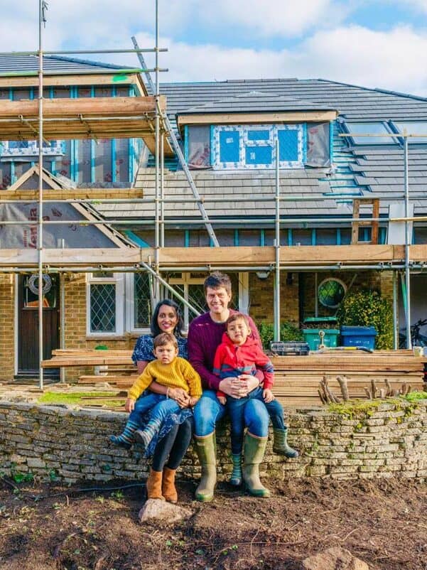 Family enjoying time outside a house under renovation with scaffolding.