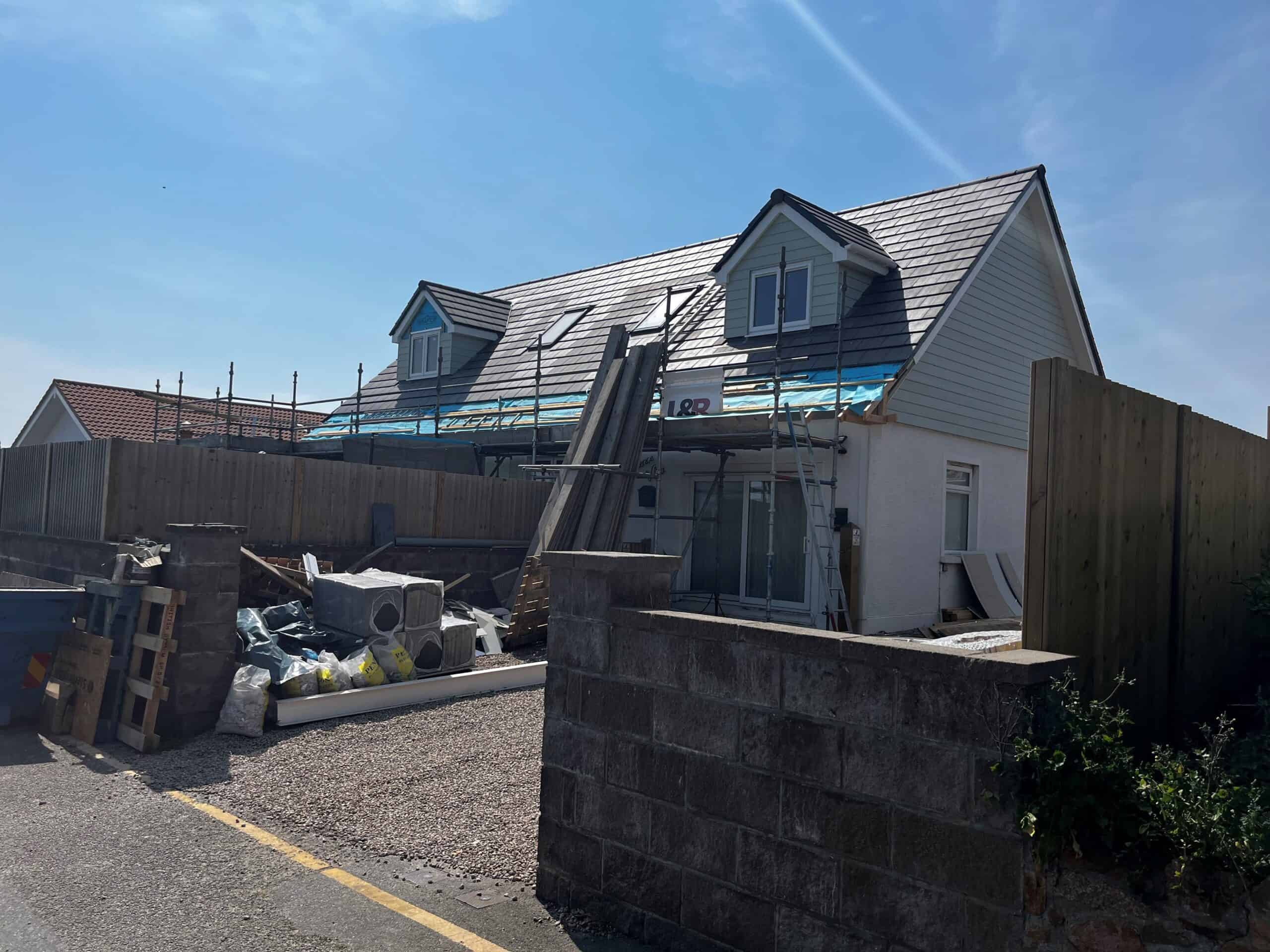 Newly renovated house with scaffolding and roofing work in progress.