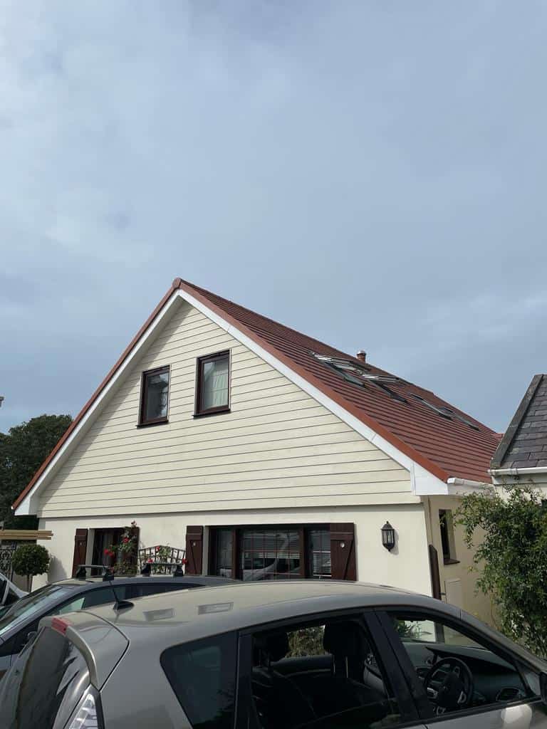 Modern house with a red tiled roof and cream exterior walls in a residential area.