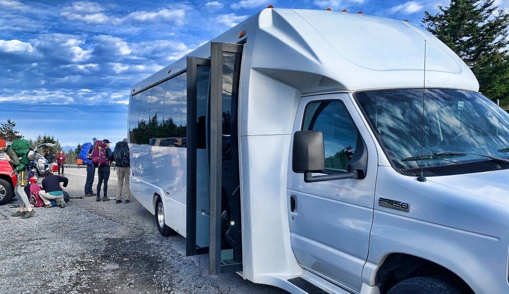 Modern white shuttle bus at Mountain Harbour, scenic mountain transportation.