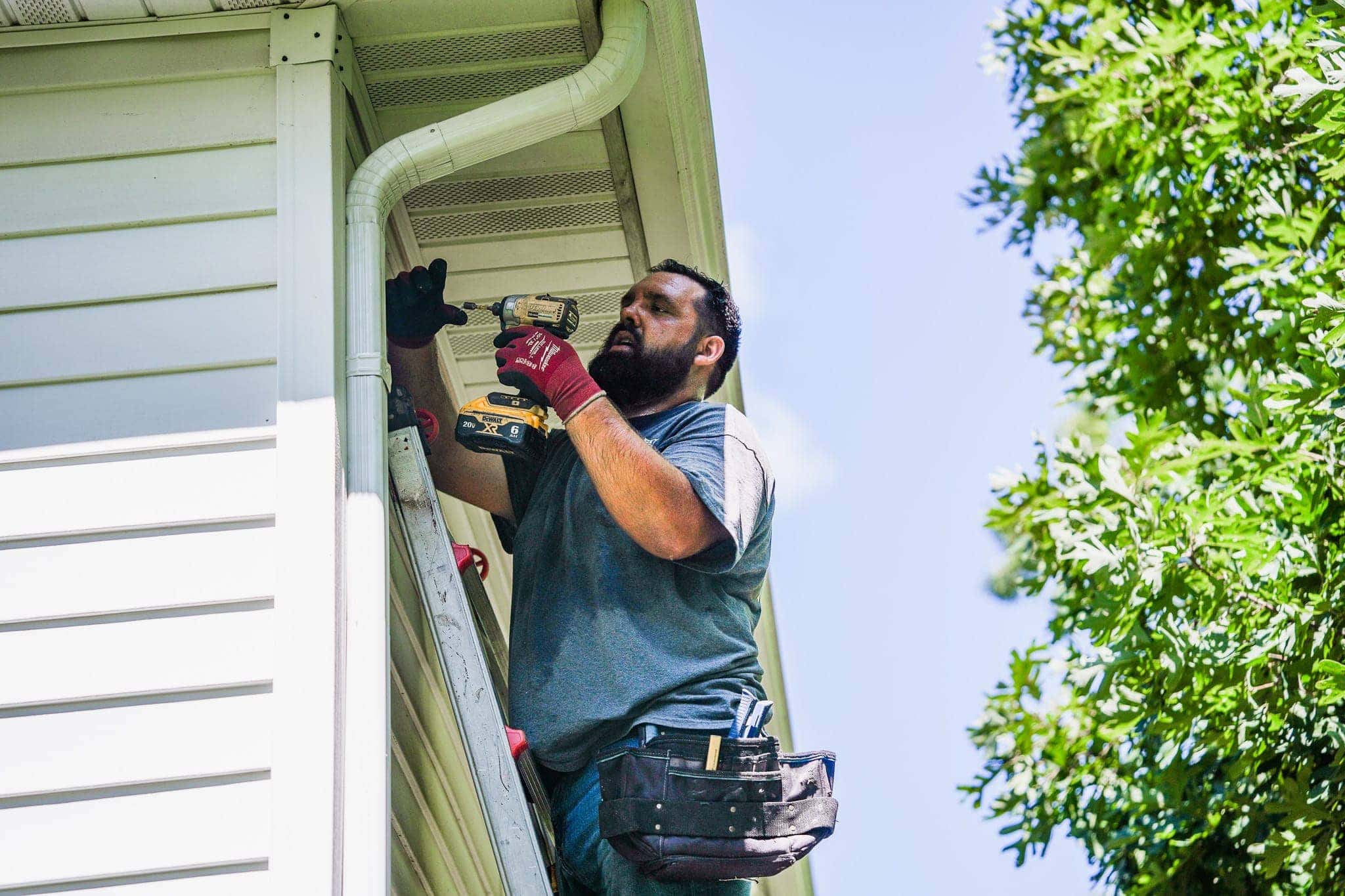 Roofing repair worker inspecting the gutter system on a house.