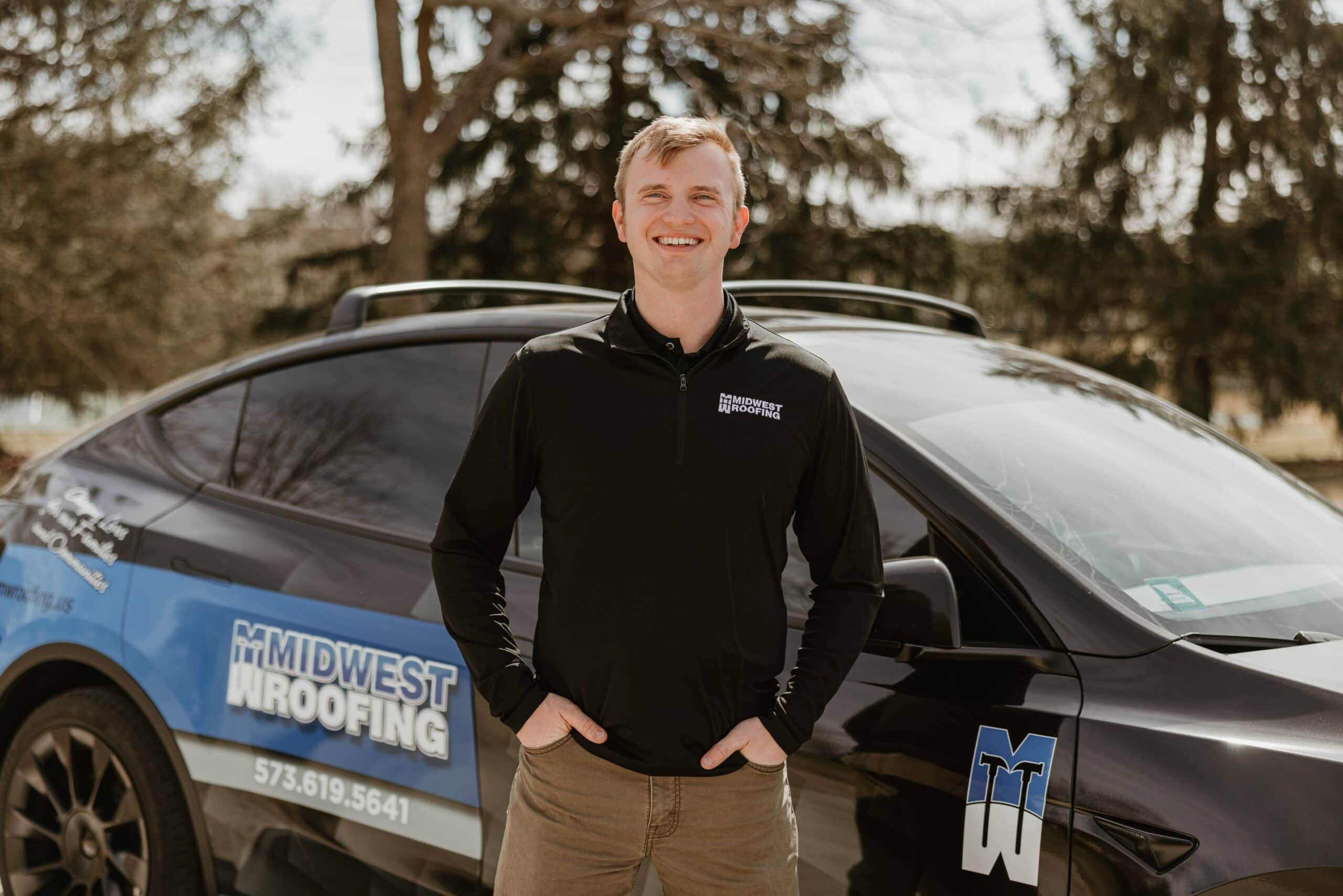 Midwest Roofing technician standing next to company vehicle outdoors.