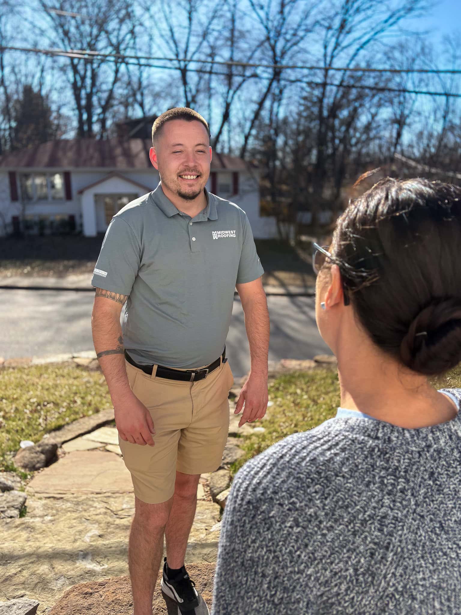 Roofing expert consulting with homeowner outdoors in residential neighborhood.