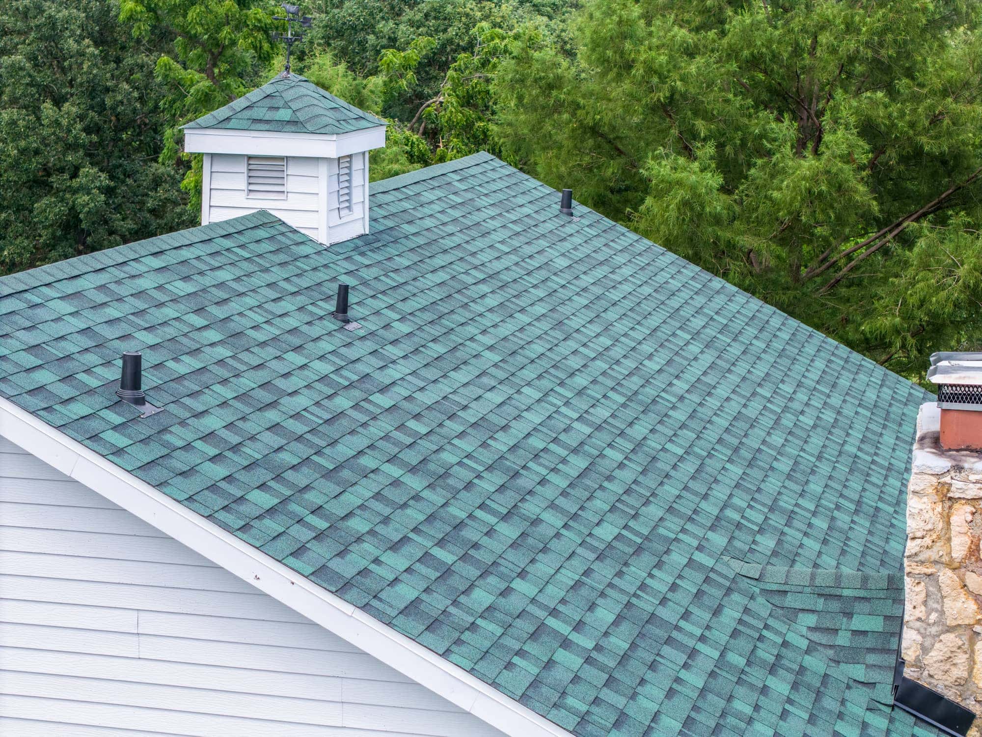 New roofing installation with green shingles on residential home in Dixon, MO.