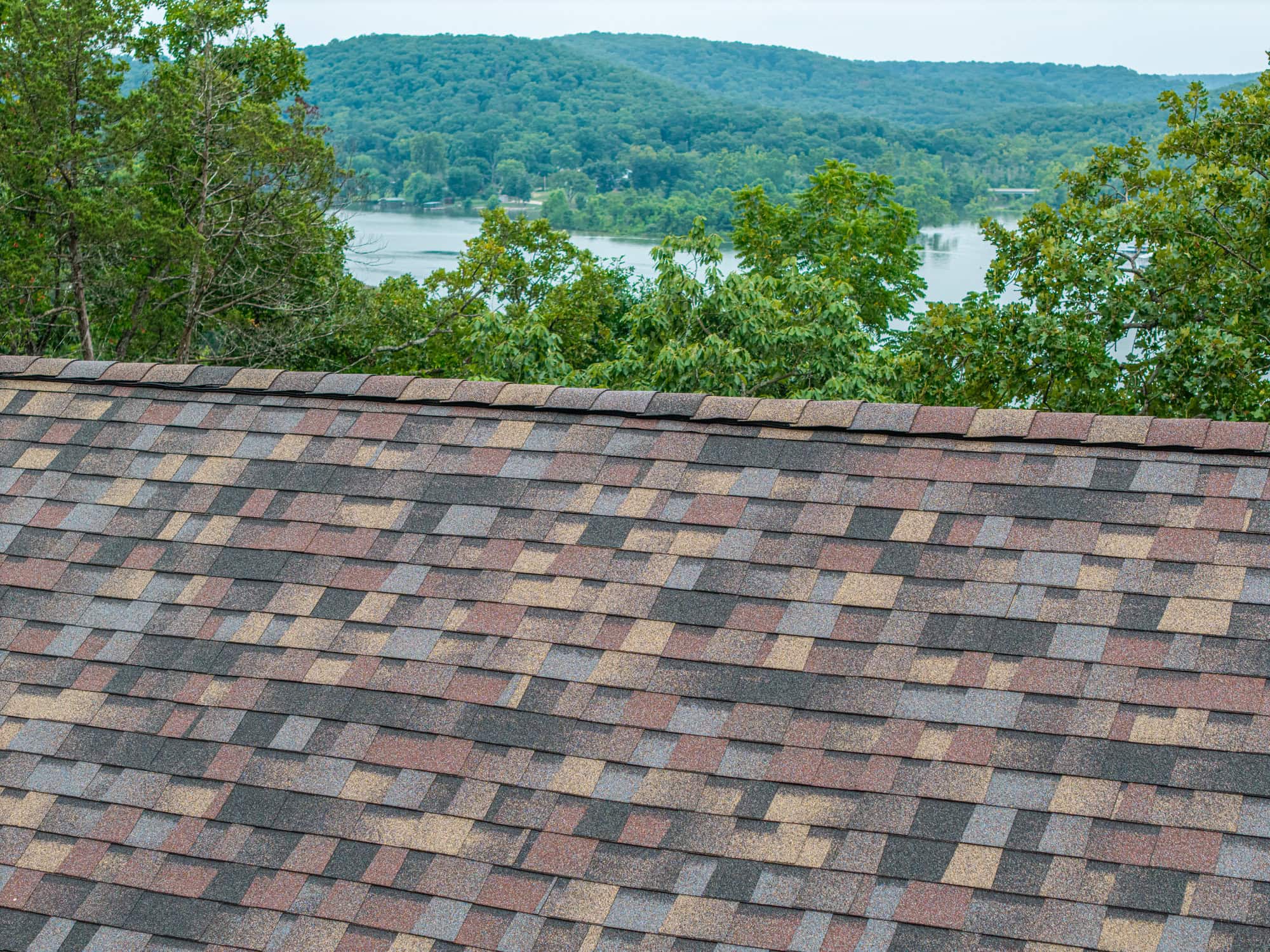 New asphalt shingle roof installed with scenic lake view in background.