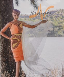 Robe mi-longue brodée, en pagne tissé saumon à brillantine or, Avec ceinture large brodée et tulles traîne brillant or. Foulard et chapeau brodé assortis.