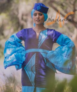 Robe longue volantée, brodée, en pagne tissé à brillantine, mix tissu batik couleur bleue turquoise et bleu. Avec ceinture large asymétrique brodée. Foulard et chapeau brodé assortis.