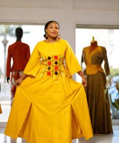 Longue robe brodé de couleur jaune moutarde avec manches 3/4 en tissu coton woodin avec des broderies à l'avant. La robe est agrémentée de fentes en bas sur chaque coté de la robe