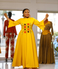 Longue robe brodé de couleur jaune moutarde avec manches 3/4 en tissu coton woodin avec des broderies à l'avant. La robe est agrémentée de fentes en bas sur chaque coté de la robe
