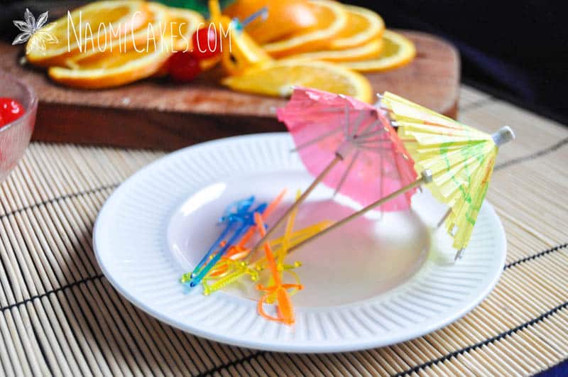 sword toothpicks and cocktail umbrellas on a white plate