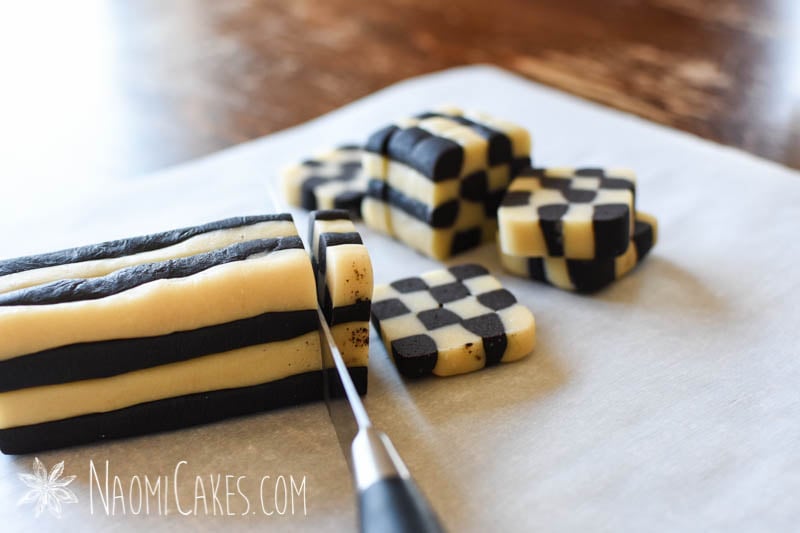slicing checkerboard cookies from a square log of dough on parchment paper