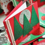 a red homemade Christmas card with trees and a glitter silver moon on it