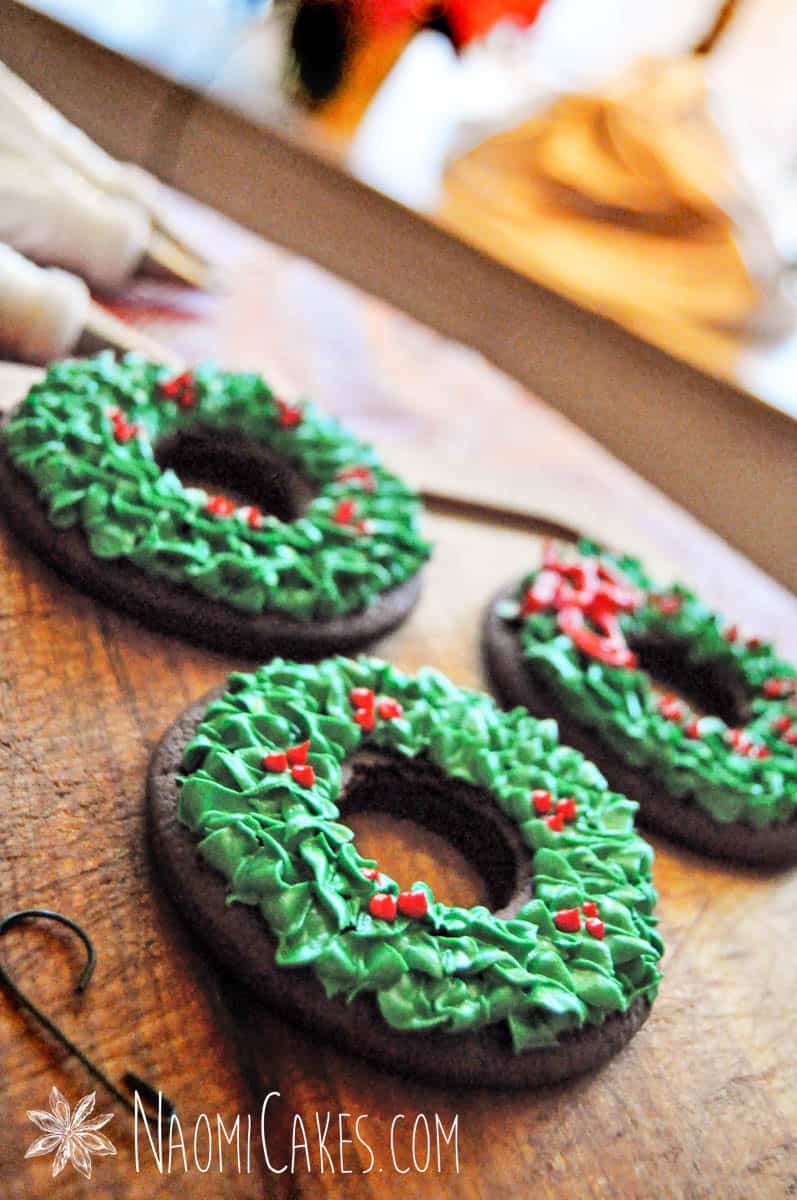 3 green wreath cookies on a wooden board for Christmas